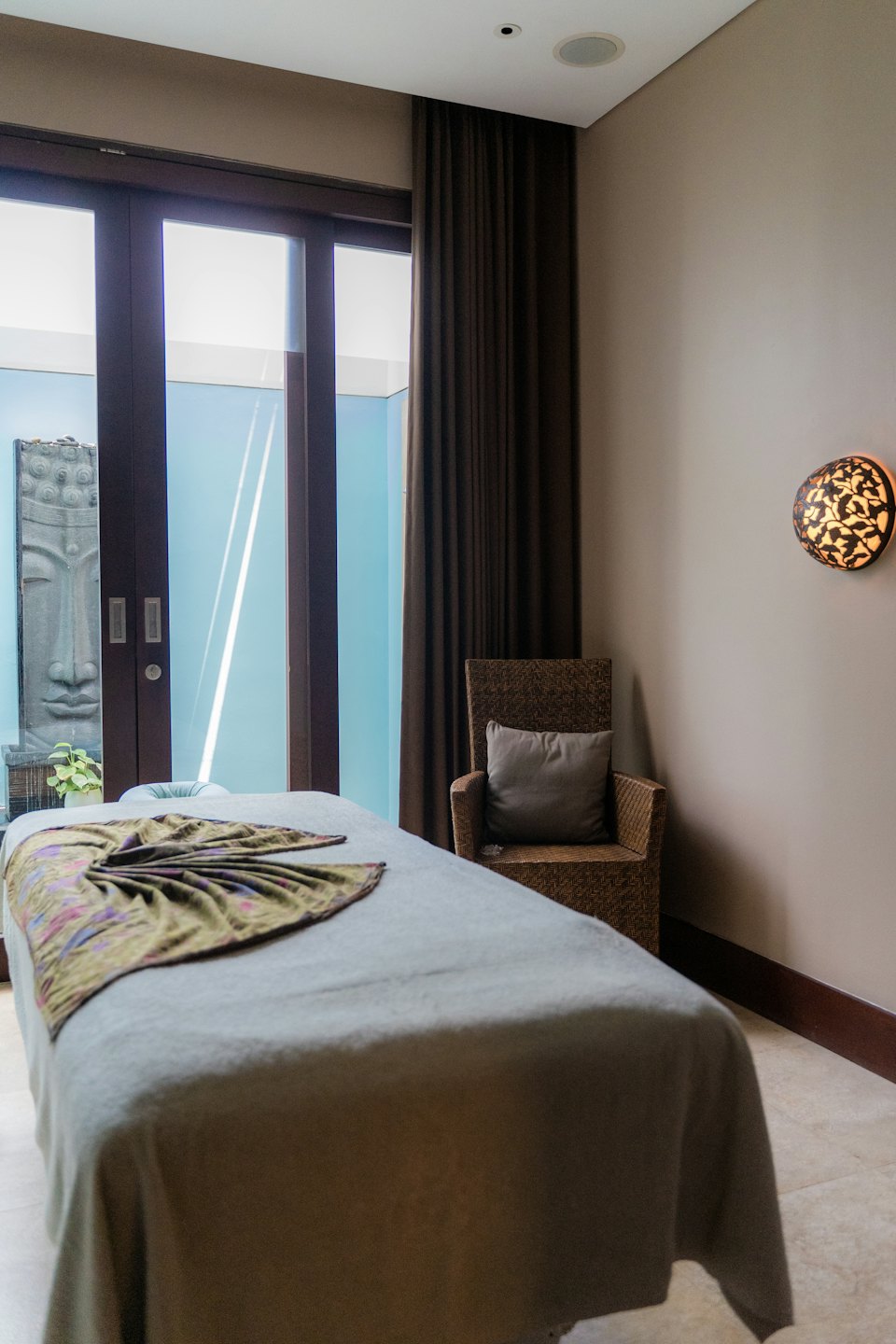 Leerer Spa-Raum mit Massageliege und Buddha-Statue.